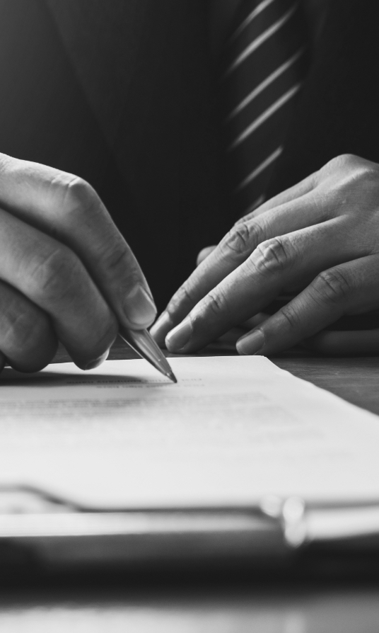 a photo of a person's hands writing on a document with a pen