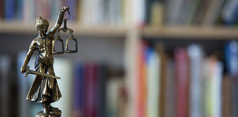 Justice figurine in front of books belonging to a New York criminal defense lawyer